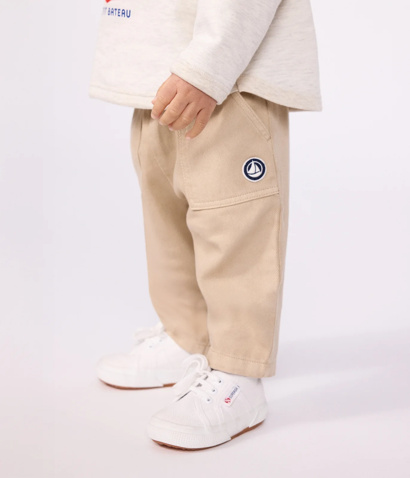 Babies' cargo-style trousers in plain cotton with a badge