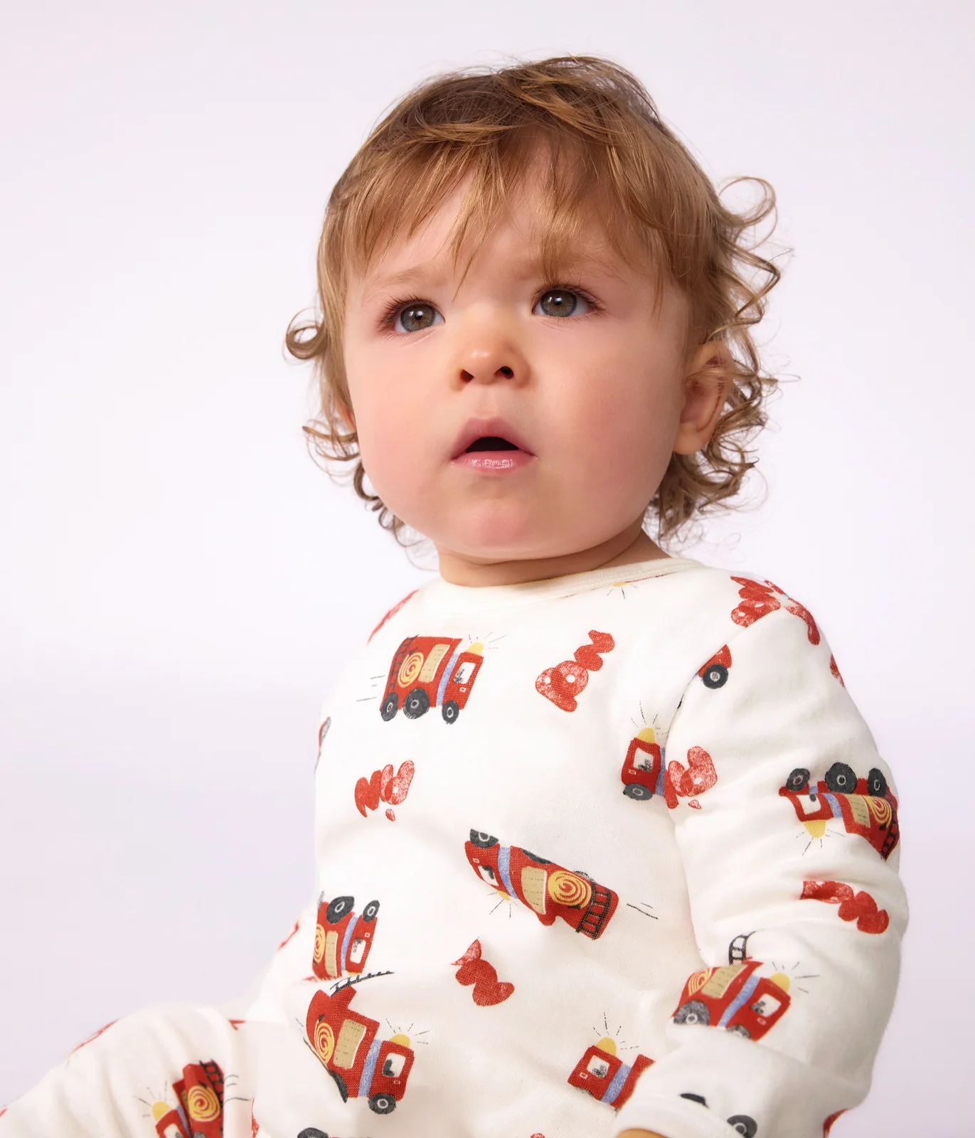 Babies' pyjama suit in tube knit fabric with a printed firefighter design and a back opening