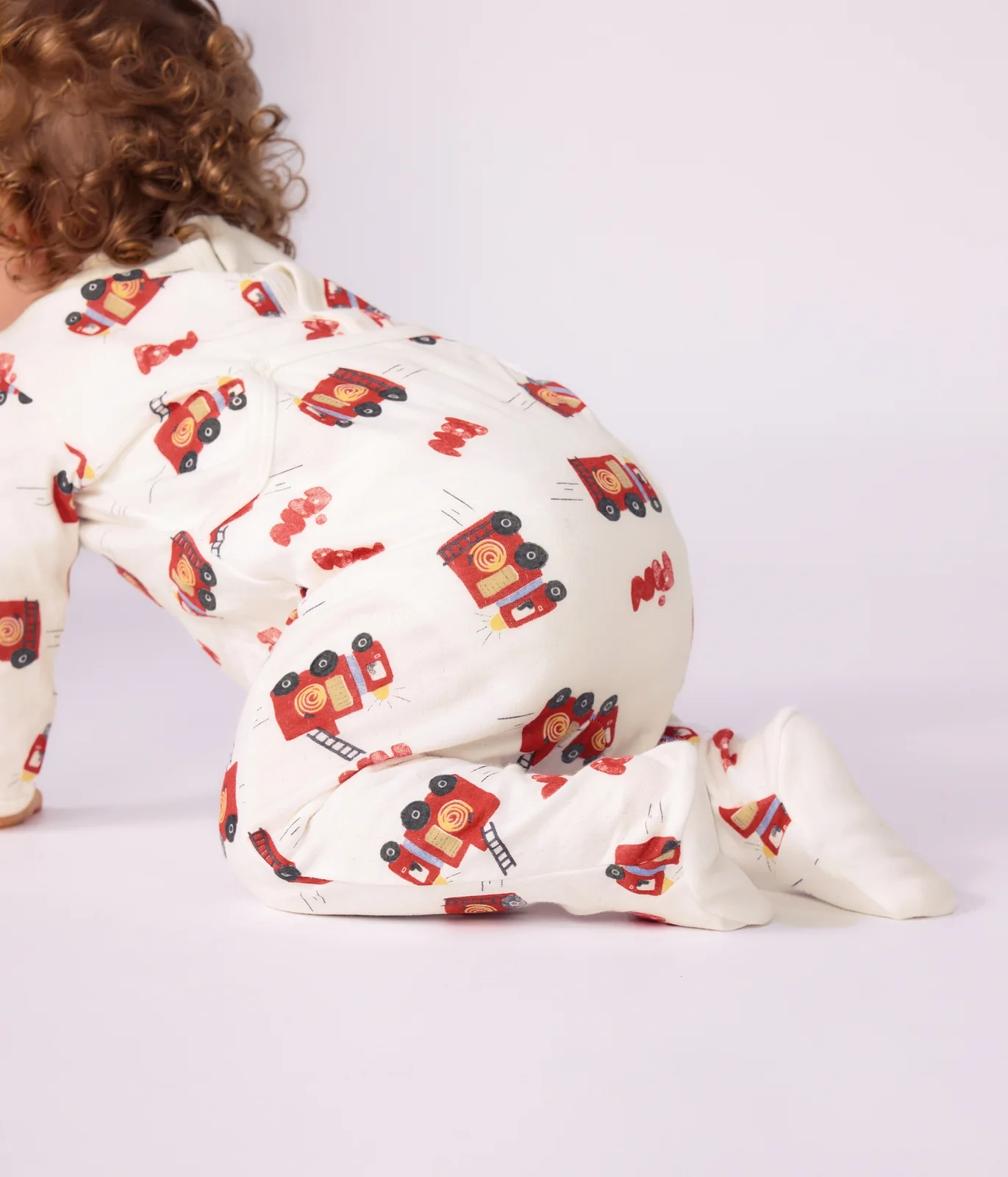 Babies' pyjama suit in tube knit fabric with a printed firefighter design and a back opening